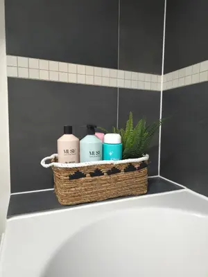 a basket with three candles on the edge of a bathroom tub at Canalside 1 bed flat in Hertford