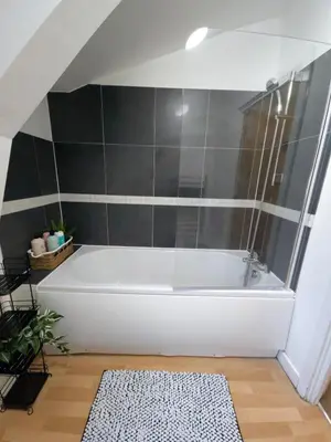 a white bath tub in a bathroom with black tiles at Canalside 1 bed flat in Hertford