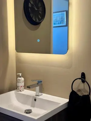 a bathroom with a white sink with a clock on the wall at Quaint Bury St Edmunds Cottage in Bury Saint Edmunds