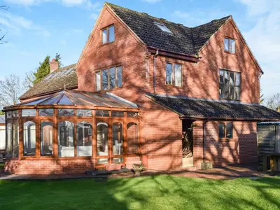 a large brick house with a conservatory at Swallowdale in Flordon