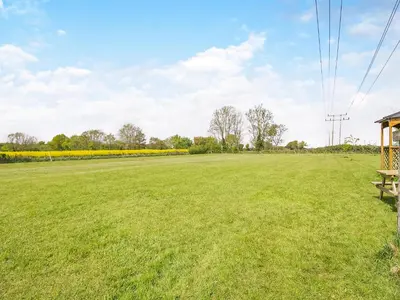 a large grassy field with a bench in the foreground at Treetops - Uk49523 in Saint Lawrence