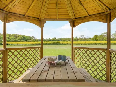a wooden table on the porch of a gazebo at Treetops - Uk49523 in Saint Lawrence