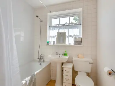 a bathroom with a sink and a toilet and a window at Island Cottage in West Mersea