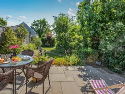 a patio with a table and chairs in a garden at Island Cottage in West Mersea