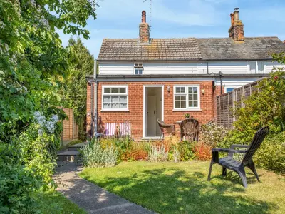 a red brick house with a bench in the yard at Island Cottage in West Mersea