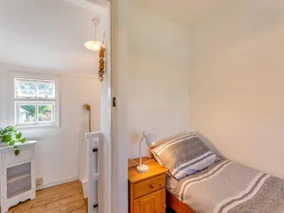 a bedroom with a bed and a dresser and a window at Island Cottage in West Mersea