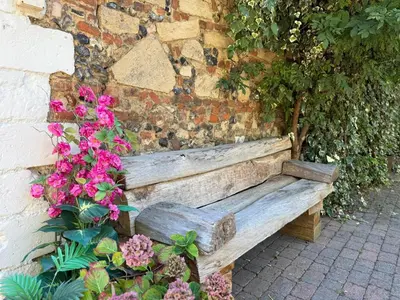a wooden bench against a brick wall with flowers at A historic Pub with a modern twist - The Greyhound in Bury Saint Edmunds