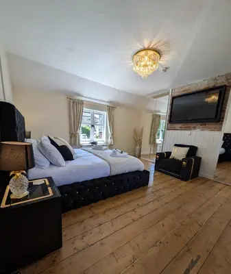 a bedroom with a large bed and a flat screen tv at A historic Pub with a modern twist - The Greyhound in Bury Saint Edmunds