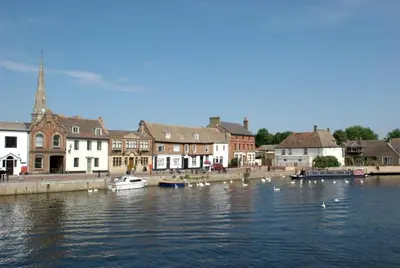 a group of boats in the water near a town at The White Barn near Cambridge in Huntingdon