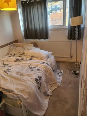 an unmade bed in a bedroom next to a window at One bed room in three bed room house in Hoddesdon