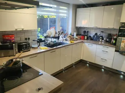 a kitchen with white cabinets and a wooden floor at One bed room in three bed room house in Hoddesdon