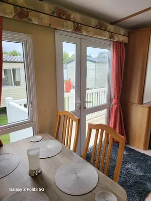 a dining room with a table and chairs and windows at Home from home in Holland-on-Sea