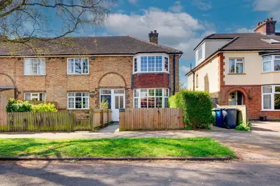 a brick house with a wooden fence in front of it at Stylish and Modern Flat with Free Parking Pass the Keys in Cambridge