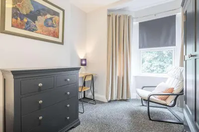 a bedroom with a dresser and a chair and a window at Modern 4-Bedroom Detached Home in Central Cambridge with Parking in Cambridge