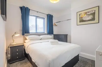 a bedroom with a bed with blue curtains and a window at Modern 4-Bedroom Detached Home in Central Cambridge with Parking in Cambridge