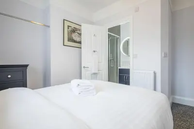 a white bedroom with a white bed and a mirror at Modern 4-Bedroom Detached Home in Central Cambridge with Parking in Cambridge