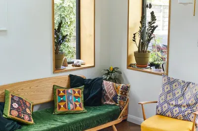 a living room with a green couch and two mirrors at The Avenue in Cherry Hinton