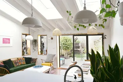 a living room with pendant lights and a green couch at The Avenue in Cherry Hinton