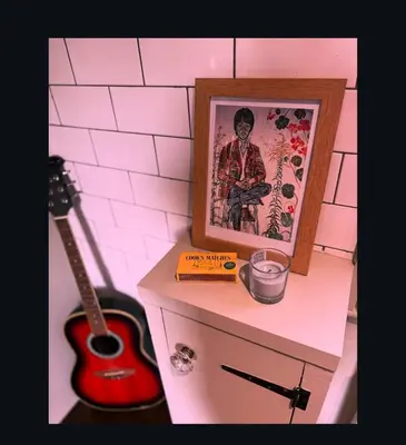 a shelf with a guitar and a picture and a book at Upstairs at Rumblebees in Felsted Station