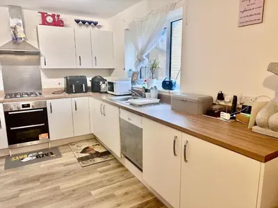 a kitchen with white cabinets and a wooden counter top at Home in Cambridge in Long Stanton