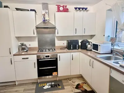 a kitchen with white cabinets and a stove top oven at Home in Cambridge in Long Stanton