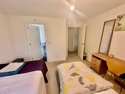 a bedroom with two beds and a dresser and a mirror at Home in Cambridge in Long Stanton