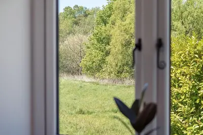a window with a view of a field of grass at The Folly, Thorpe Forest in Brettenham