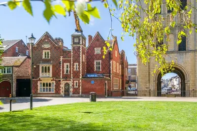 a large brick building with a clock tower at Tower Cottage - Medieval Grid Townhouse in Bury Saint Edmunds
