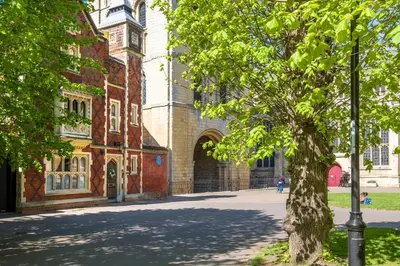 a tree in front of a building with a clock tower at Tower Cottage - Medieval Grid Townhouse in Bury Saint Edmunds