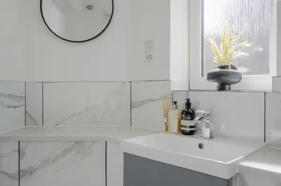 a white bathroom with a sink and a mirror at 2 Luxurious Apartments with Free Parking near Chelmsford City in Chelmsford