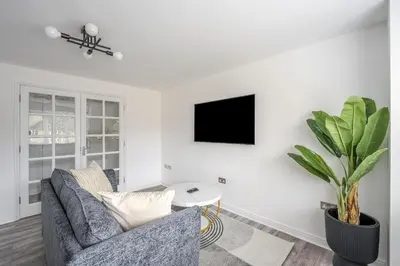 a living room with a couch and a tv on a wall at 2 Luxurious Apartments with Free Parking near Chelmsford City in Chelmsford