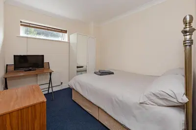 a bedroom with a bed and a desk with a television at Spacious 3 bed flat in Colchester - Free parking in Hythe