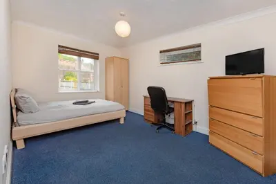a bedroom with a bed and a desk and a television at Spacious 3 bed flat in Colchester - Free parking in Hythe