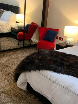 a bedroom with a bed and a red chair and a mirror at Two Bed Flat By The Beach No Parties No Events in Southend-on-Sea