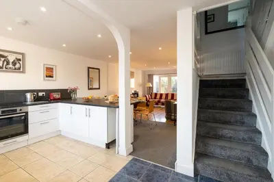 a kitchen and living room with a staircase in a house at 7 The Plantation - Aldeburgh Coastal Cottages in Aldeburgh