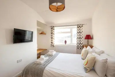 a bedroom with a bed and a tv on a wall at 7 The Plantation - Aldeburgh Coastal Cottages in Aldeburgh