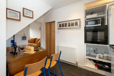 a kitchen and living room with a table and chairs at 7 Coastguards Cottages - Aldeburgh Coastal Cottages in Aldeburgh