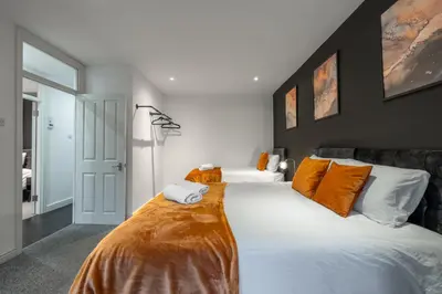 a bedroom with a large white bed with orange pillows at Modern Comfort 4BR Home for 10 in North Weald