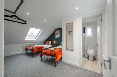 a bedroom with a bed and two chairs and a toilet at Modern Comfort 4BR Home for 10 in North Weald