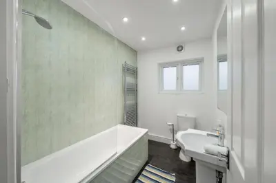 a white bathroom with a tub and a sink at Modern Comfort 4BR Home for 10 in North Weald