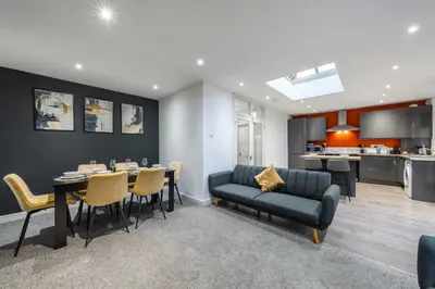 a living room with a couch and a dining room at Modern Comfort 4BR Home for 10 in North Weald