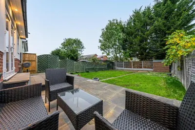 a patio with chairs and a table and a yard at Modern Comfort 4BR Home for 10 in North Weald