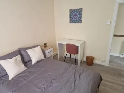 a bedroom with a bed with a chair and a desk at Arundel Road, RM30RX in Harold Wood