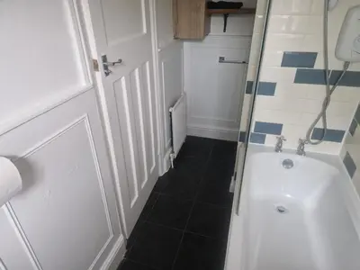 a small bathroom with a shower and a tub at Arundel Road, RM30RX in Harold Wood