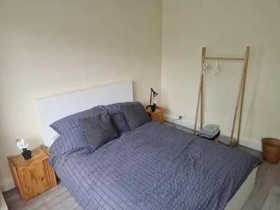 a bed with a blue comforter in a bedroom at Arundel Road, RM30RX in Harold Wood