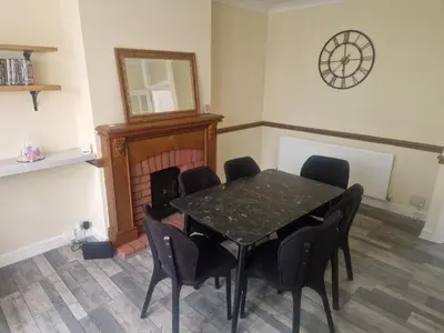 a dining room with a table and chairs and a clock at Arundel Road, RM30RX in Harold Wood