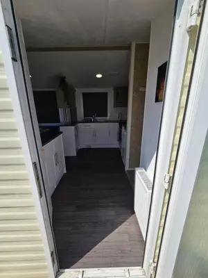 a hallway leading to a kitchen with white cabinets at FI005 Loomy Escapes Caravan at St Osyth Beach Essex in Saint Osyth
