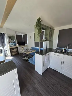 a kitchen with white cabinets and a living room at FI005 Loomy Escapes Caravan at St Osyth Beach Essex in Saint Osyth