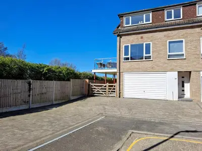 a parking lot in front of a house with a garage at Modern townhouse with easy access to London in Ingatestone