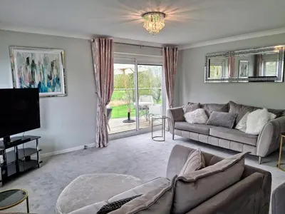 a living room with a couch and a tv at Modern townhouse with easy access to London in Ingatestone